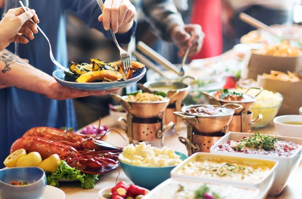 Colorful birthday party food spread with pizza, fruit, and cupcakes arranged on festive table