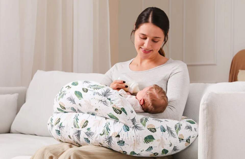 Cozy mom using memory foam nursing pillow for relaxed breastfeeding session with newborn.
