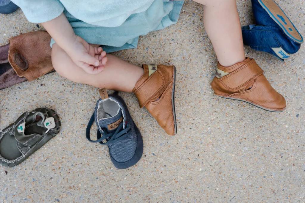 Toddler walking confidently in flexible shoes designed for broad foot shapes.