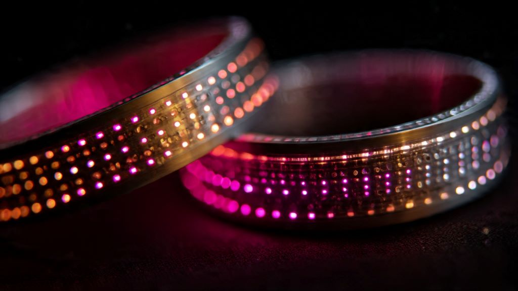 2. Close-up of paired vibrating bracelets showing LED lights illuminating as they receive connection signals from distant sibling