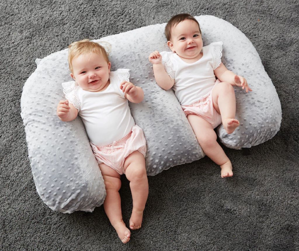 Happy family with twins on ergonomic memory foam nursing pillow during tandem feed.
