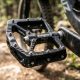 A sleek black titanium mountain bike pedal mounted on a carbon crank arm.