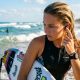 Surfer holding board on sunny Florida beach with ocean waves.