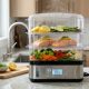 Stainless steel electric steamer with colorful vegetables on a kitchen counter.