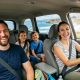 Smiling children looking out a car window on a scenic California road trip.